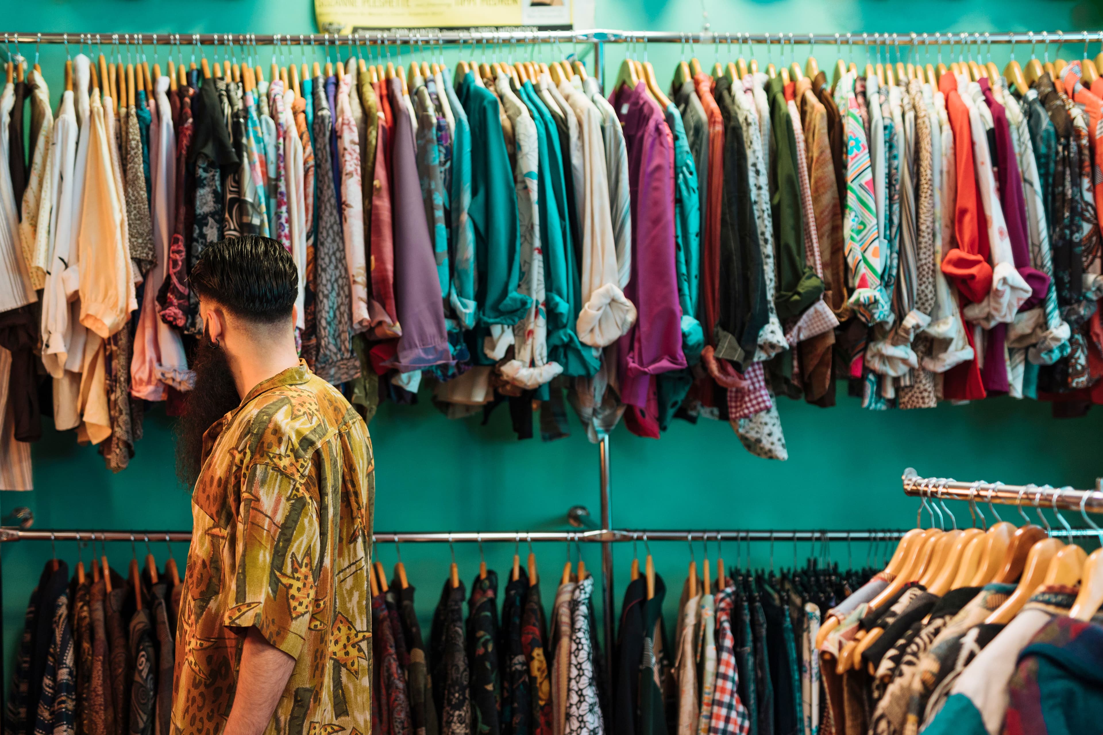 l'immagine rappresenta un uomo che sceglie delle magliette in un negozio di second hand