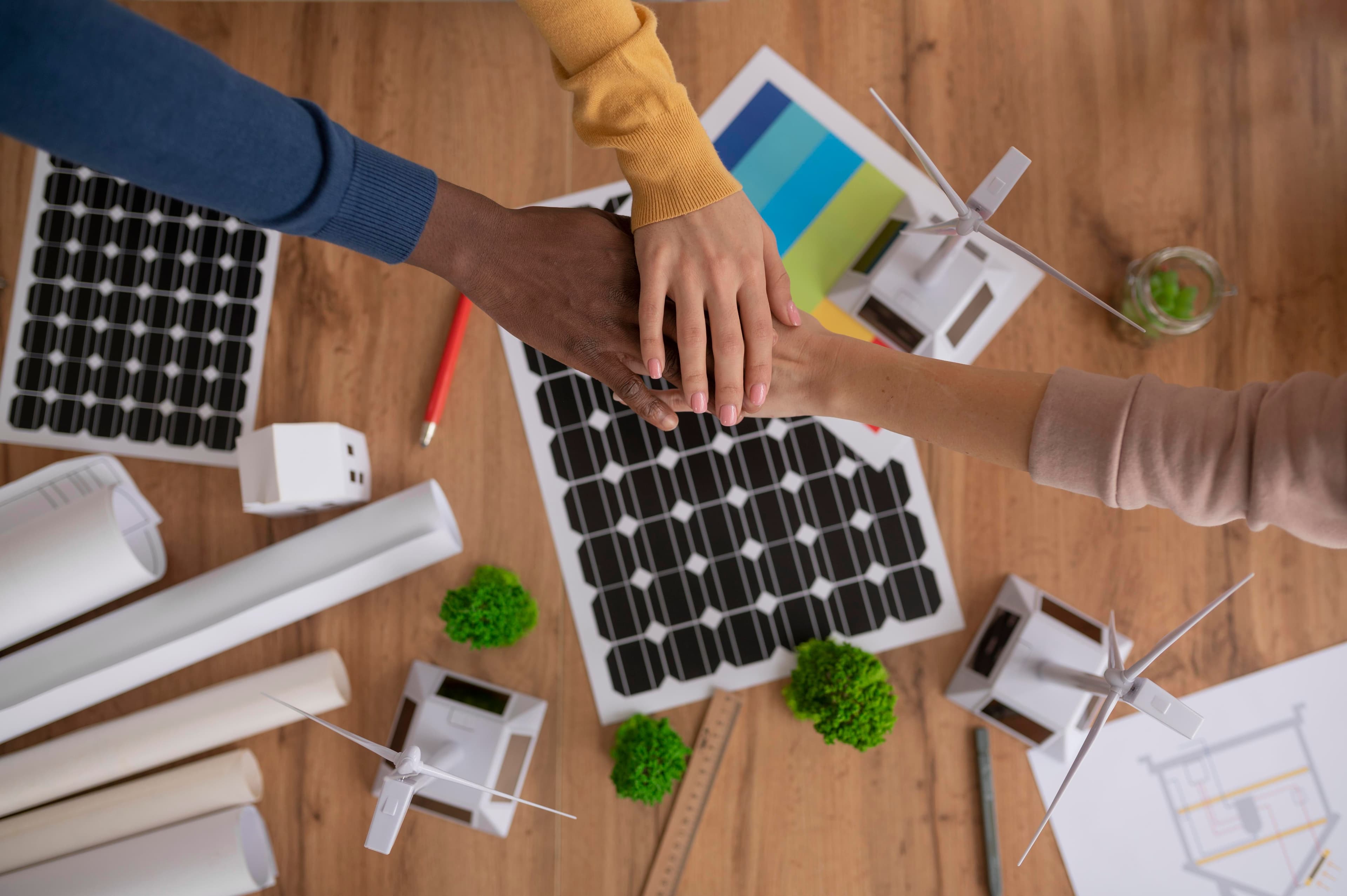 l'immagine rappresenta le mani unite di tre persone su uno sfondo che rappresenta l'energia rinnovabile